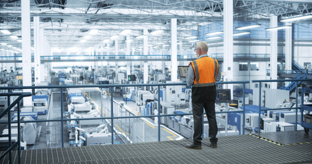 Aufkleber - Industrial Engineer Working at a Technology Factory. Middle Aged Male Using Laptop Computer at Work, Browsing Electronics Information Online. Man's Back in Safety Vest Turned to Camera