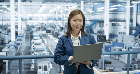 Portrait of a Beatiful Electronics Manufacture Engineer Smiling, Looking at Camera. Young Japanese Female Using Laptop Computer for Online Research, Monitoring Artificial Intelligence Systems