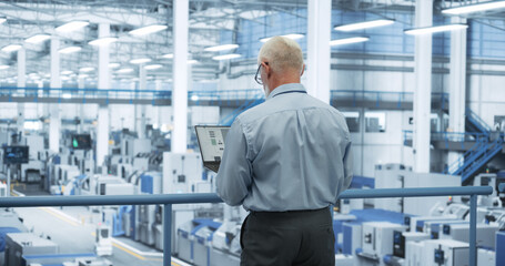 Fototapete - Middle Aged Engineer Monitoring and Analyzing Conditions at an Automated Modern Electronics Factory with Mobility Robots Working with the Help of Artificial Intelligence Software