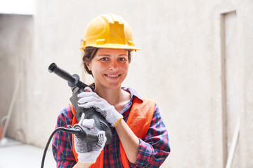 Portrait of smiling young female skilled engineer wearing workwear carrying equipment at construction site