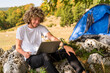 Young happy man freelancer working online using laptop in nature.