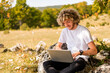Young happy man freelancer working online using laptop in nature.