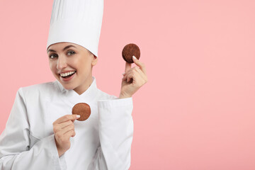 Wall Mural - Happy professional confectioner in uniform holding delicious macarons on pink background. Space for text