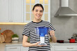 Woman holding filter jug with water in kitchen