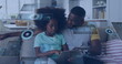 Image of data over happy african american father and daughter using tablet relaxing at home