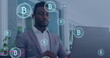 Image of data processing and bitcoin symbols over african amercian businessman using laptop