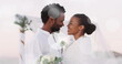 Image of light spots over happy african american bride and groom embracing on beach at wedding