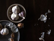 Garlic bulbs and peels in earthy bowls on dark background