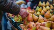 A person in a market stall is selecting a bunch of fresh pears from a colorful display