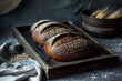 Freshly baked dark bread on a wooden tray over dark background