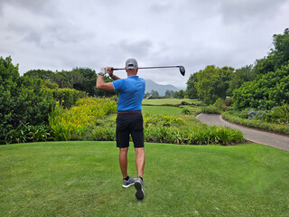 Wall Mural - Man Swinging Golf Club on Lush Green Field