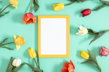 Wall Mural - festive floral background. beautiful tulip flowers and yellow empty photo frame on a pastel mint bac