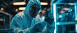 The design engineer of a ultramodern electronic manufacturing facility examines the microchip with gloves while wearing sterile coveralls.