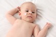© New Africa - Cute little baby with cream on face on white blanket, above view