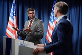 Fototapeta  - Confident mature multiethnic male politician in formalwear and eyeglasses looking at opponent during discussion of political issues
