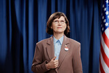 Fototapeta  - Mature brunette female candidate taking part in pre-election campaign looking at camera while standing against American flag