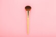 New big makeup brush with soft bristles on light pink table background. Pastel color. Female beauty product. Closeup. Top down view.