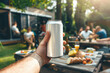 © Dmitrii - Hand presenting a white drink can at a backyard BBQ