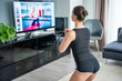 Young woman is doing fitness at home in living room while watching and participating in a class