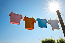 T-shirts Hanging On A Clothesline In Front Of Blue Sky And Sun