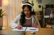 © DragonImages - Smart schoolgirl listening to music in headphones when doing math homework