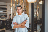 Fototapeta Mapy - Happy asian professional Hairdresser or hair stylist man standing confidence with arm crossed with smile and holding hairdressing equipment while looking at camera in beauty salon and barber shop
