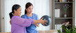 Asian caregiver woman or nurse training senior woman lifting sport ball with hands for exercise while physical therapy and rehabilitation, caretaker or physiotherapist helping elderly workout.
