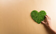 Hands holding green heart on brown background. World environment day, earth day and save earth concept.