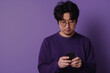 © AI_images - Against a calming purple background, an attentive Japanese man is typing a text message on a smartphone app, maintaining his online presence with ease and efficiency.