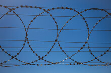Barbed Wire Fence Against Clear Blue Sky.
