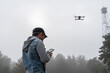 man controls a remote control of a UAV against the sky and a high old tower for monitoring forests. Modern technologies in monitoring forest fires.