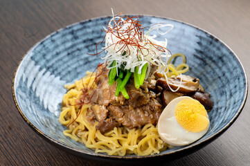 A bowl of noodles with beef, mushrooms, and a soft-boiled egg.