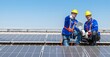 Two solar panel engineers wearing safety gear are inspecting a rooftop solar panel installation.