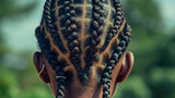 Close-up of a child’s head from behind, showing a pattern of complex braids on dark hair.