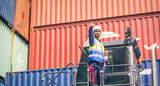 Fototapeta Na sufit - Engineer team wears PPE checking container storage with cargo container background at sunset. Logistics global import or export shipping industrial concept.