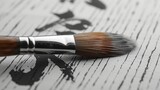 An image of a hand holding a brush and writing calligraphy