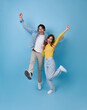 © NaMong Productions - happy young Asian teen couple dancing enjoy and listening to music playlist together romantic love isolated on blue studio background..