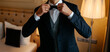 groom in elegant tuxedo arranging his jacket.