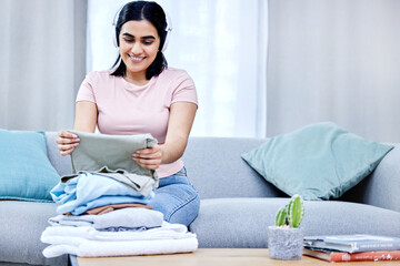 Wall Mural - Woman, headphones and laundry clothes in home for neat lounge, smiling and fabric on table. Female cleaner, house and sitting on sofa folding, happy and listening to music while cleaning apartment