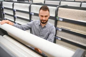 Wall Mural - Male builder choosing wallpapers in hardware store