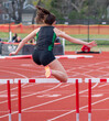 Rear view of a female running in a hurdle race outdoor