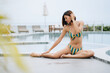 Young asian woman in bikini sitting at the poolside