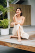 Attractive asian woman in a beige dress is sitting outdoors