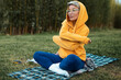 cute girl with glasses in an orange hoodie is sitting in a park in nature expressing kind emotions