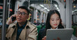 People sitting next to each other. Asian man and woman using their personal digital devices. Male with glasses talking on smartphone. Woman actively typing on tablet. Train turning.