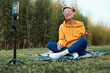 a pretty blogger girl in glasses and an orange hoodie is sitting in a park in nature, streaming on her phone and emotionally chatting with subscribers, expressing kind emotions