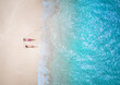 Aerial top down view of a couple in swimsuits sunbathing on a beautiful tropical beach in the Caribbean with turquoise sea