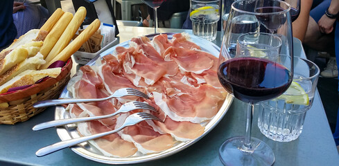 Close up view of plate of Prosciutto di San Daniele Crude Italian Ham near Udine in Friuli-Venezia Giulia, Italy, Europe. Appetizer dish served with local red wine and crispy dry bread grissini