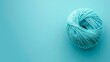   A ball of yarn sits atop a light blue surface, featuring a white yarn ball in its center