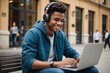 © ThomasLENNE - Smiling College student with headphones texting at laptop